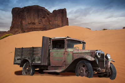 Vintage car on desert against sky