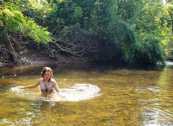 Young woman in river at forest