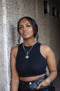 Portrait of young woman standing against wall