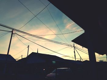 Low angle view of silhouette cables against sky during sunset