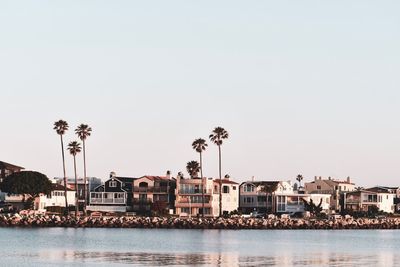 Buildings by sea against clear sky