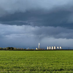 View of factory field against cloudy sky