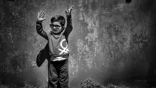 Boy wearing sunglasses while standing against wall