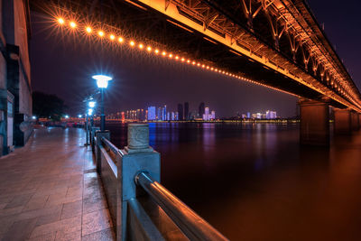 Illuminated bridge over river at night