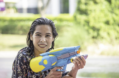 Portrait of woman holding squirt gun outdoors