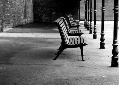 Empty bench in park against buildings in city