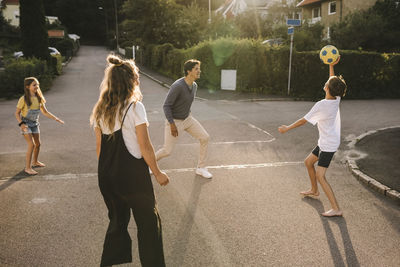 Parents playing with children on road during sunny day