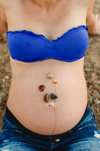 Midsection of pregnant woman with shells on stomach