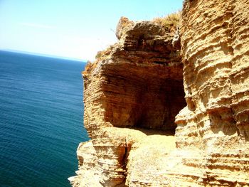 Rock formations by sea against clear sky