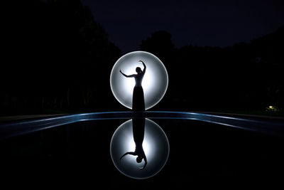 Woman dancing against light painting at night