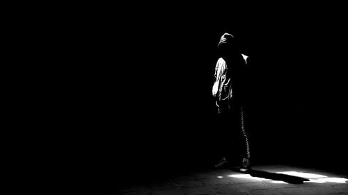 Rear view of person standing against black background