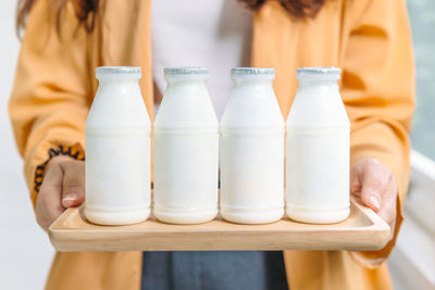 Midsection of woman holding milk bottles