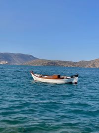 Boat in sea against clear blue sky