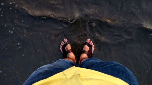 Low section of man standing in sea