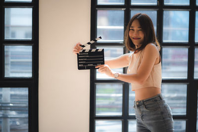 Portrait of woman standing against window