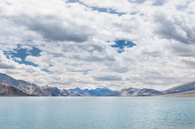 Scenic view of pangong lake by mountains against cloudy sky