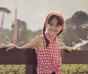 Portrait of smiling girl standing by wooden railing against sky