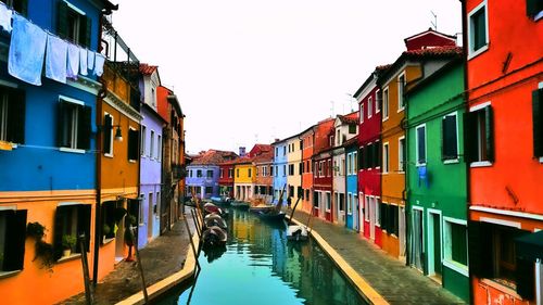 Canal amidst buildings against sky in city