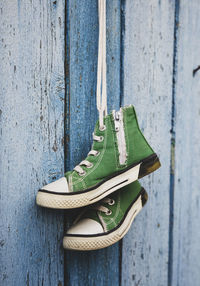 Close-up of green shoes hanging by fence