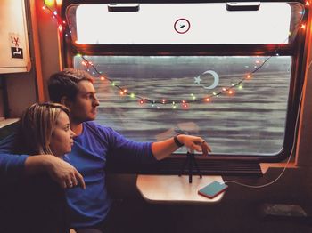 Couple looking through window while sitting in train