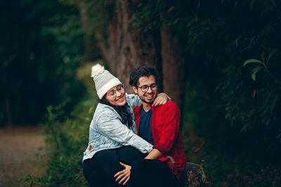 Young man smiling while sitting on tree