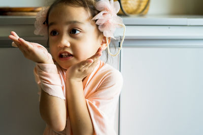 A little girl is standing in a beautiful dress with hair accessories. pretend play at home.