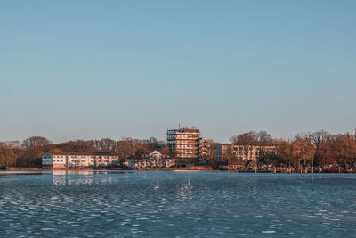 Sea by buildings against clear sky