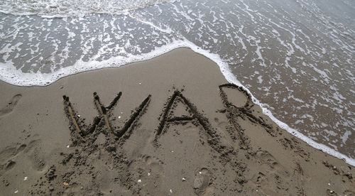 Big war text and the wave of the sea that wants to erase it on the beach