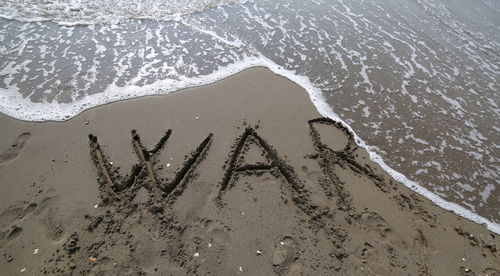 Big war text and the wave of the sea that wants to erase it on the beach