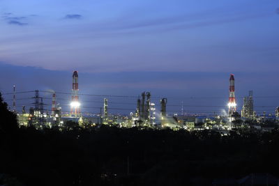 Illuminated factory against sky at night