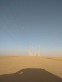 Electricity towers on najran desert land against clear sky with 4wd shadow 