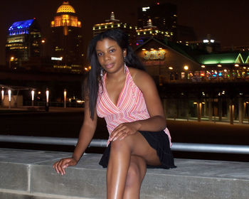 Portrait of smiling woman sitting in city at night