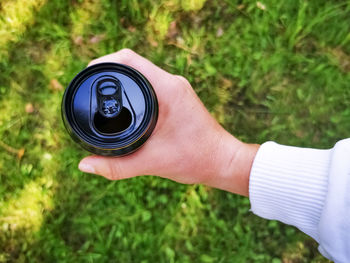 Hand holds a black tin can top view