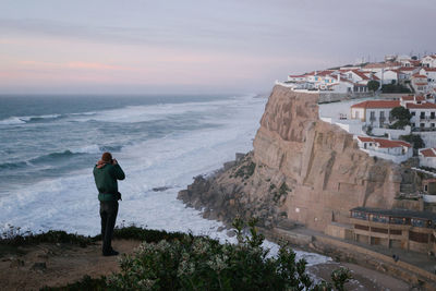 Rear view of man standing on beach against sky