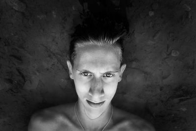 Close-up portrait of shirtless young man against wall