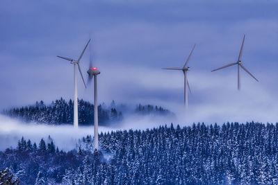 Wind turbines on field against sky