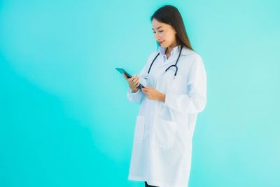 Young woman using mobile phone against blue background