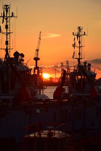 Silhouette sailboats at harbor against sky during sunset