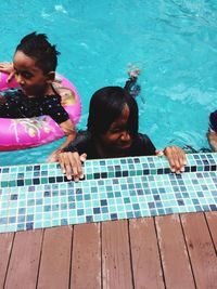 High angle view of friends sitting on swimming pool