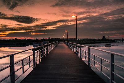 Bridge over sea against sky during sunset