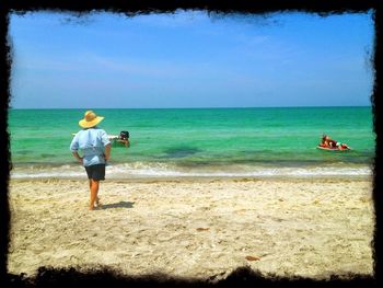 Rear view of man on beach against sky