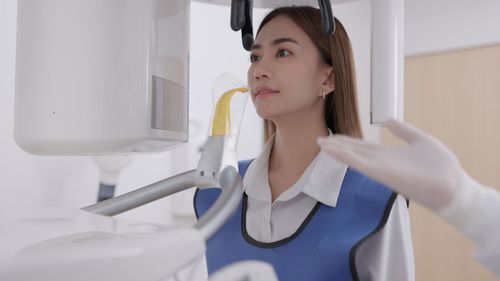 On a panoramic x-ray machine, the dentist aligns the bite of a woman.