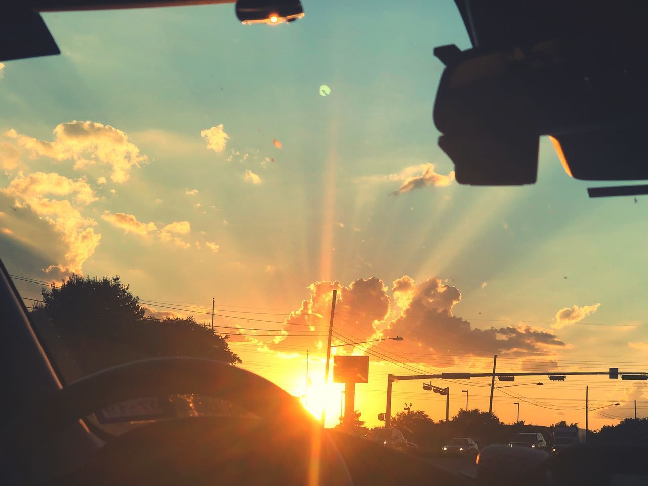 SUNSET SEEN THROUGH WINDSHIELD OF CAR