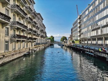 Canal amidst buildings in city against sky
