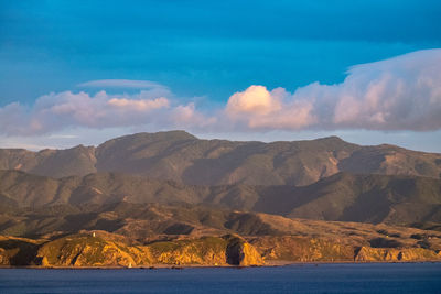 Scenic view of mountain by sea against sky