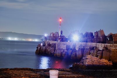 Man standing on groyne in sea against sky