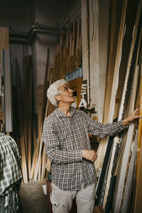 Male senior entrepreneur selecting wood while standing at workshop