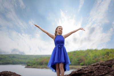 Woman with arms raised against sky