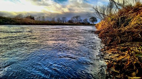 Scenic view of river against sky at sunset