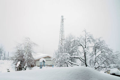 Snow covered trees and buildings against sky